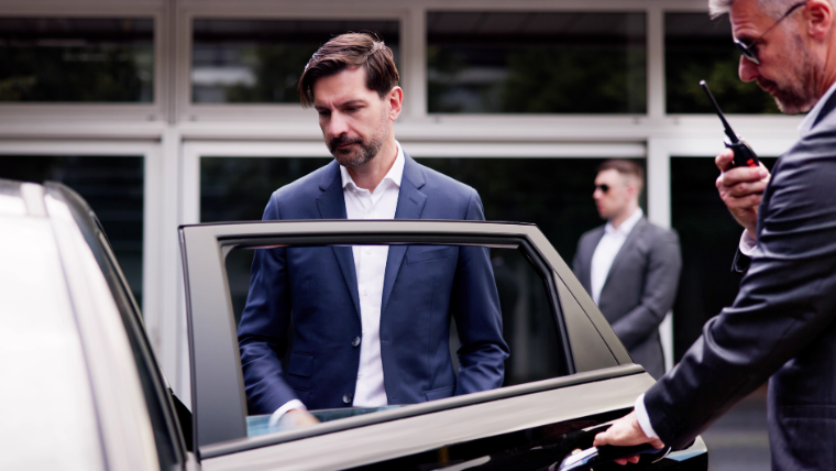 Professional chauffeur opening door for executive in navy suit exiting luxury sedan