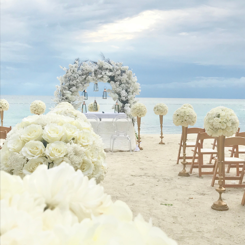 Elegant beachfront wedding ceremony setup with white floral arch and ocean backdrop in South Florida