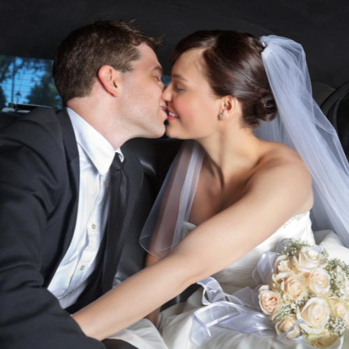 Bride and groom sharing a kiss in the back of a luxury limousine after their South Florida wedding ceremony