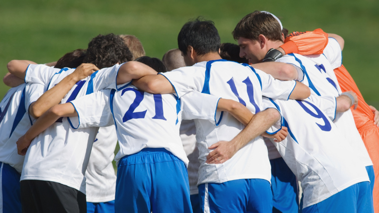Youth soccer team huddled together before a game, coordinating group travel across South Florida